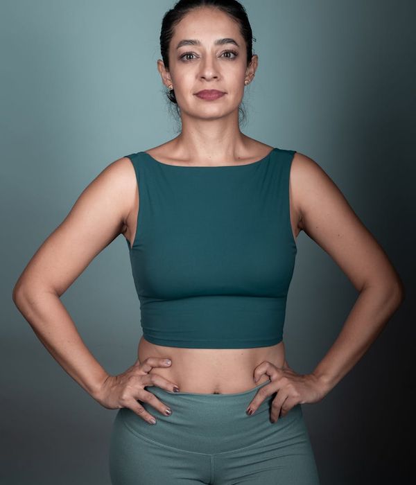 Woman in a calm yoga pose in a dark studio with lime green light.